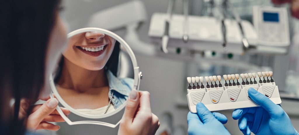 Woman looking at teeth whitening service in mirror
